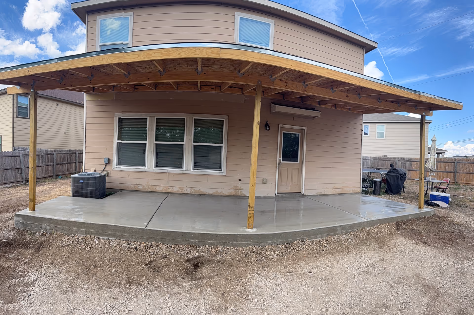 Two-story house with a large covered patio supported by wooden posts.