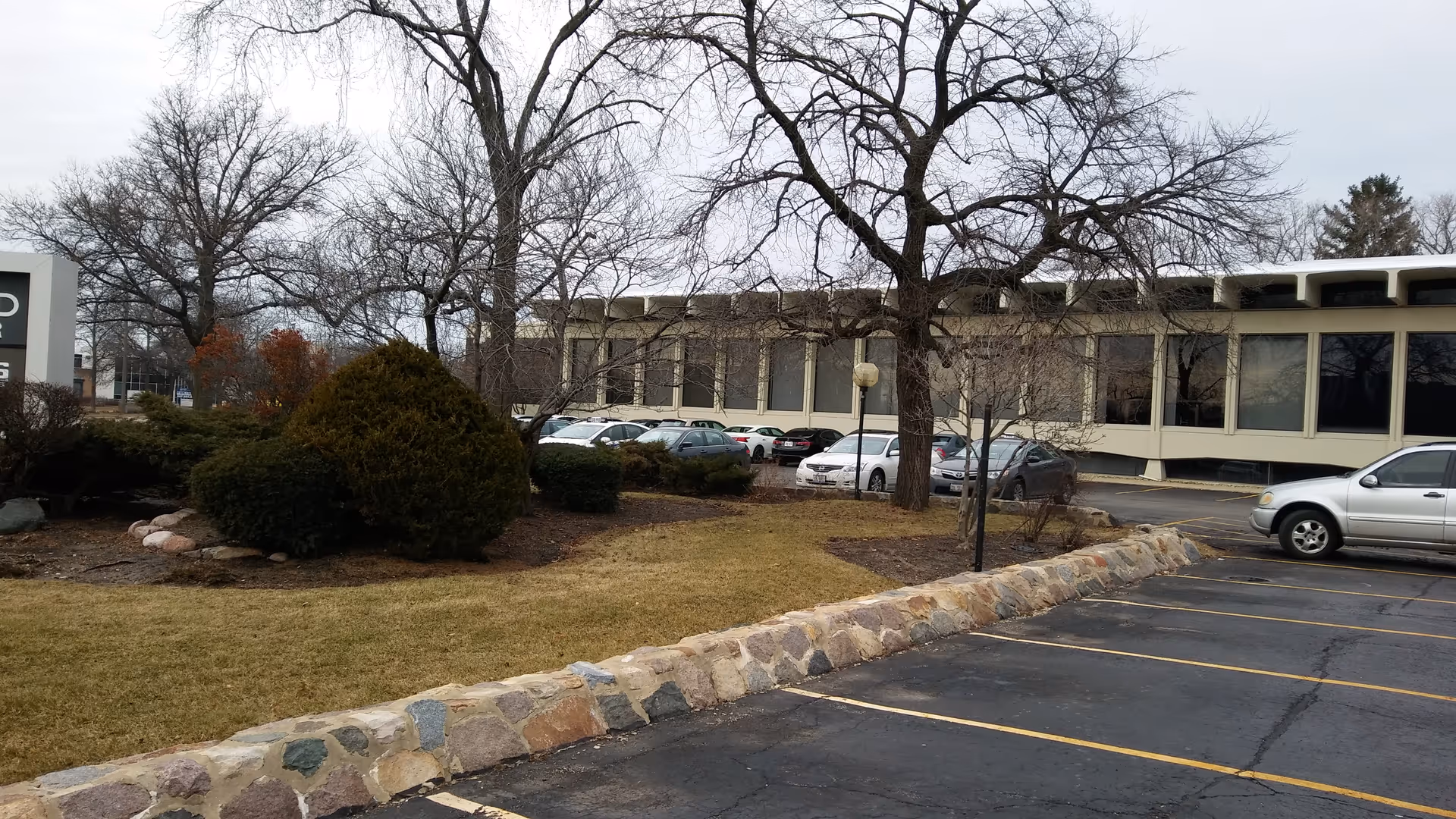 Exterior view of a senior living facility with a parking lot and landscaping.