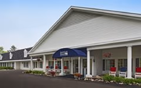 Front of American House Dearborn Heights senior living facility with a covered entrance and outdoor seating.