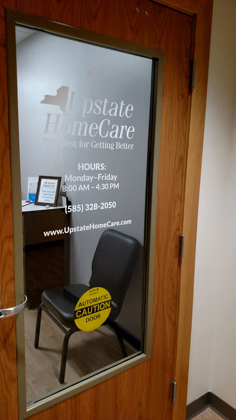 Glass door with Upstate HomeCare branding and a chair inside an office.
