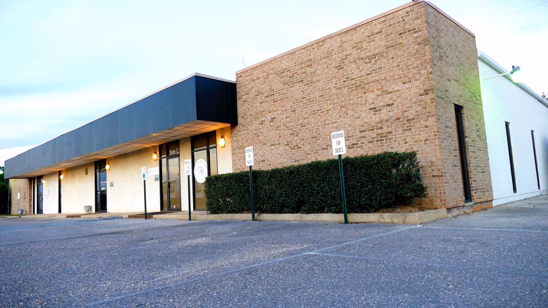 Exterior view of Promise Care Senior Care building with brick facade and parking lot.