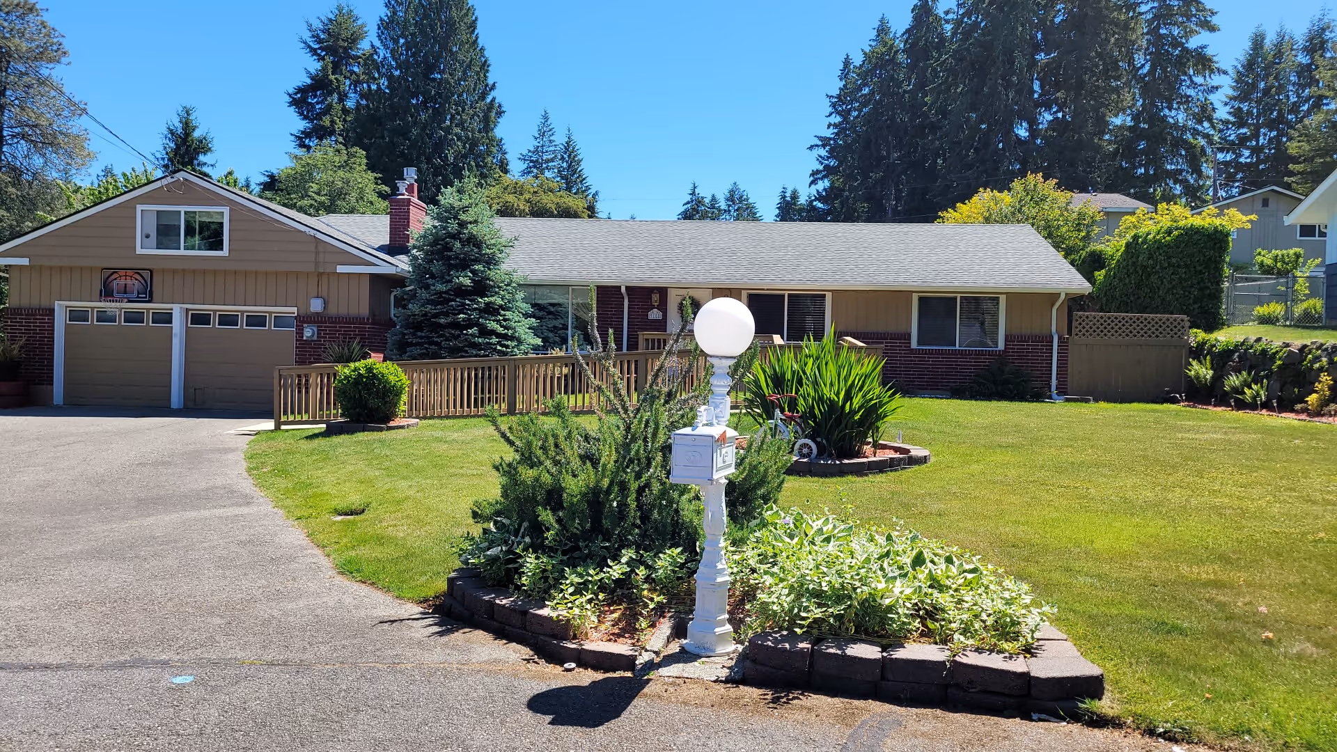 One-story residence with tan siding, well-kept lawn, and ornamental lamppost.