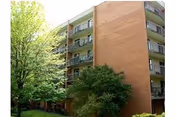 Exterior view of a multi-story brick senior living building with balconies and trees.
