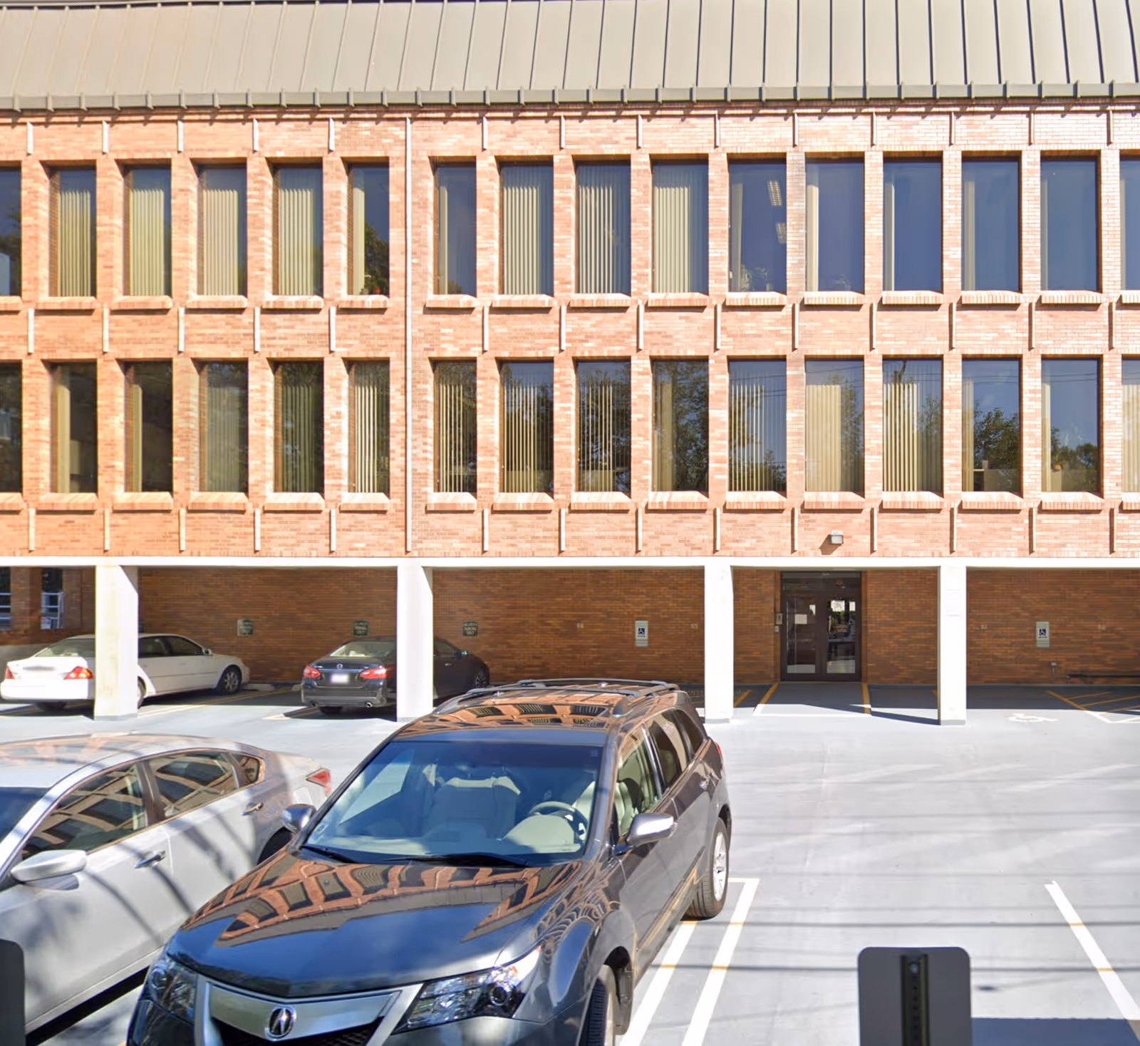 Brick senior living building facade with numerous windows and parked cars in front.