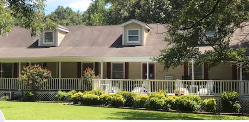 Senior living facility exterior with a long porch and green lawn.