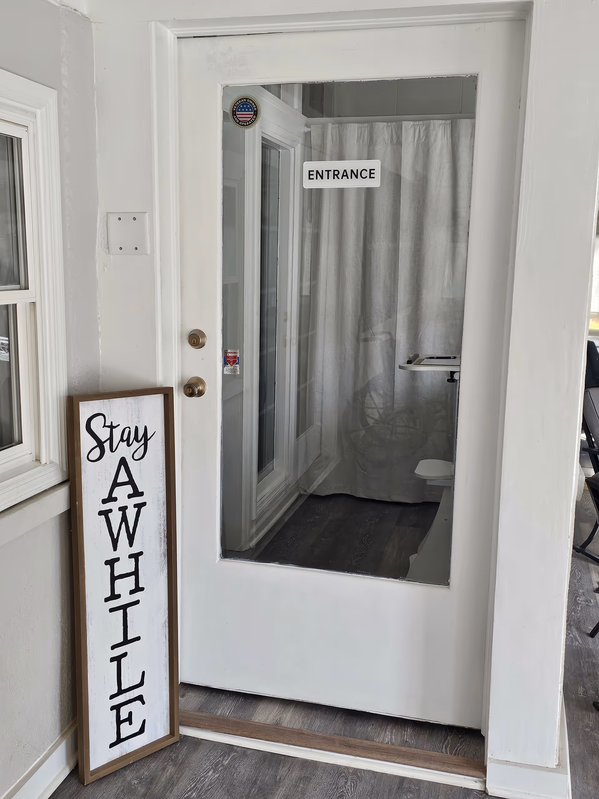 Front entrance of a senior care facility with a Stay AWHILE sign beside the door.