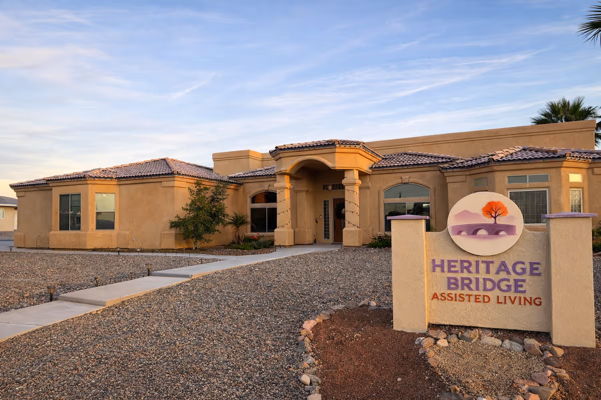 Exterior view of Heritage Bridge Assisted Living with arched entrance and sign.