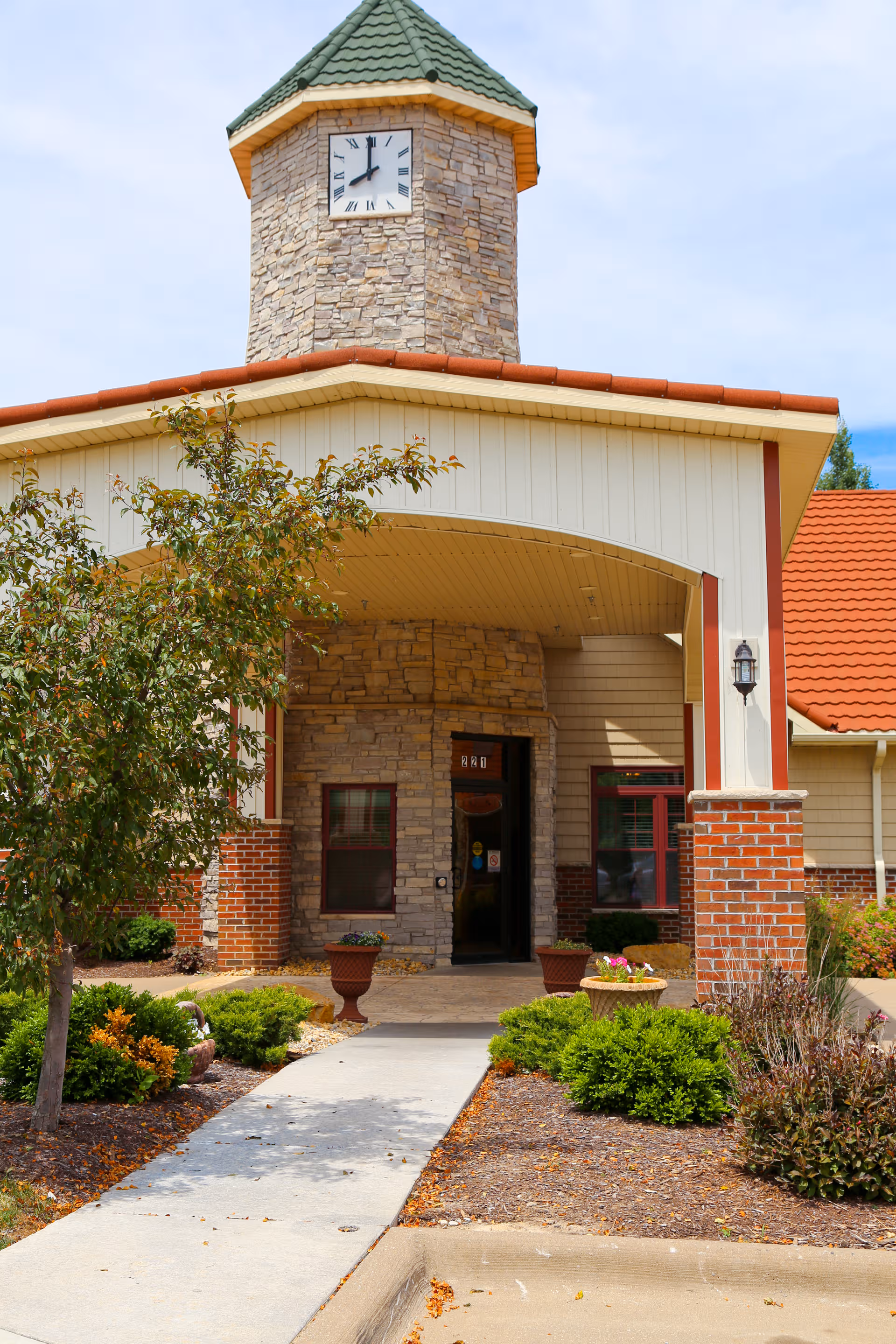 Front entrance of Charter Senior Living of Moline featuring a stone clock tower and landscaping.