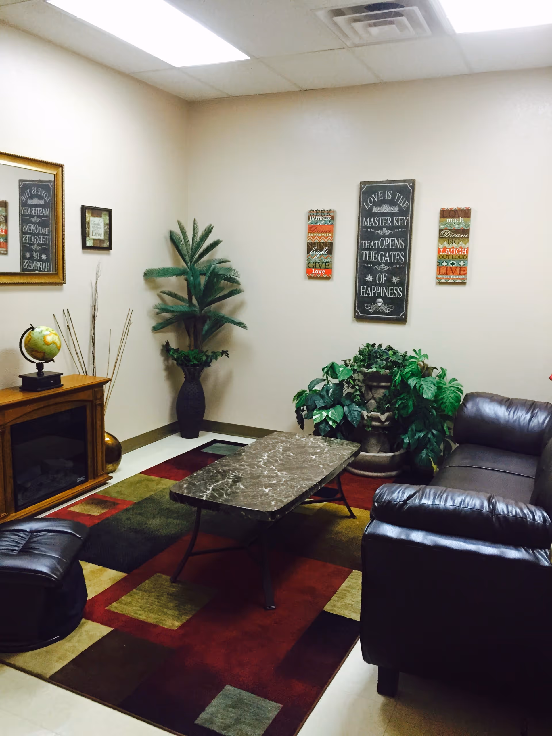 Cozy senior living lounge with leather sofas, plants, and a marble coffee table.