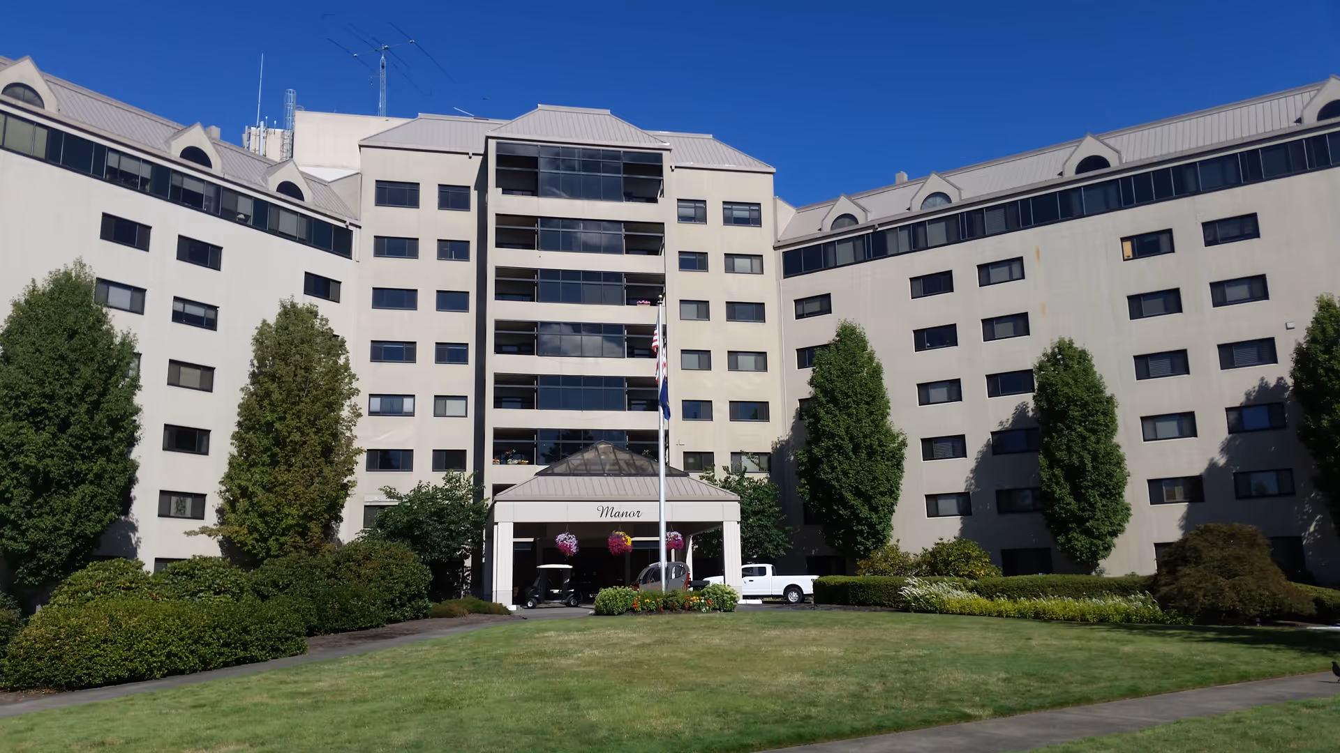 Facade of a large senior living building with a manicured lawn and entrance canopy.