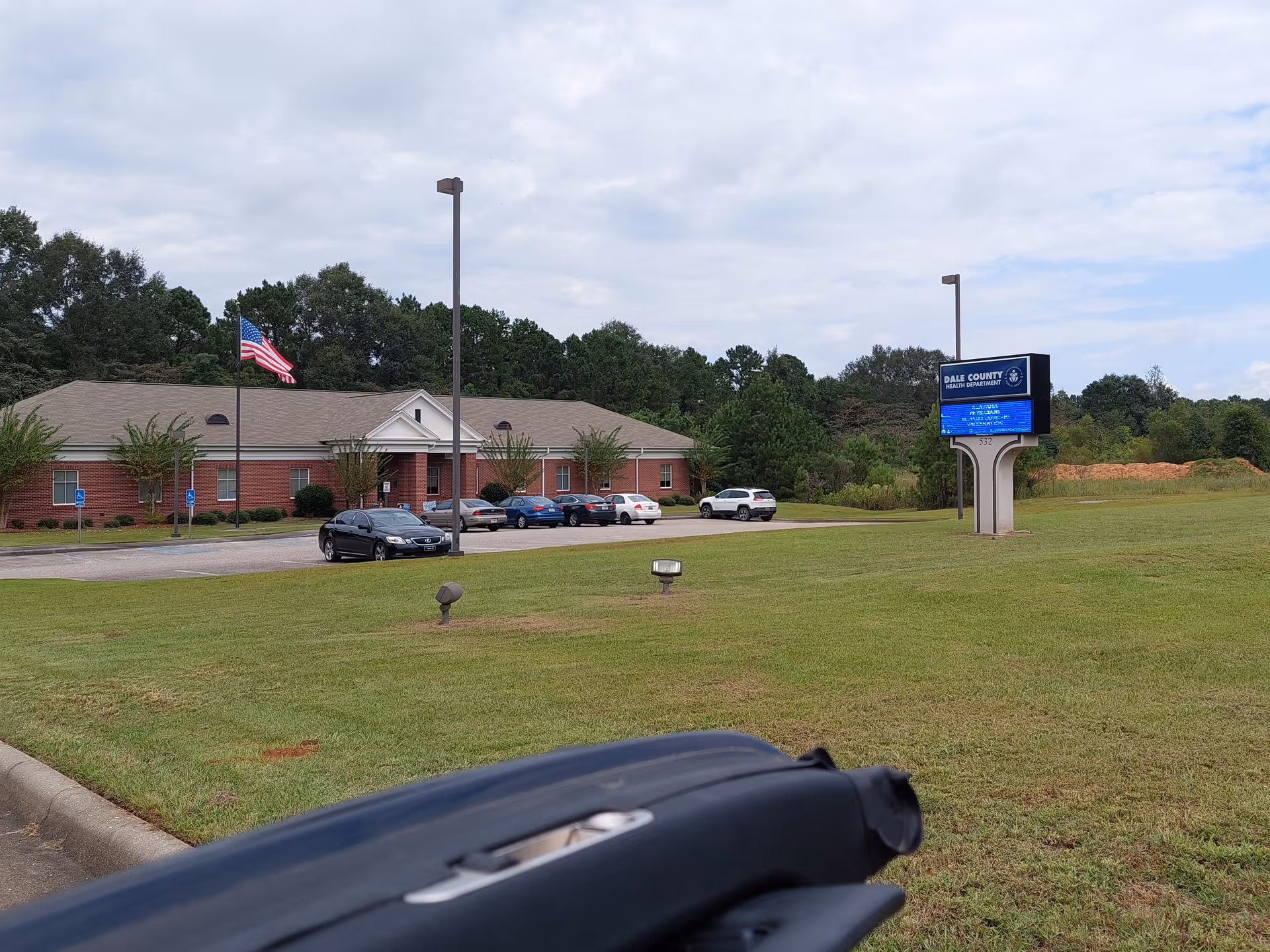 Exterior view of Dale County Health Department building with parking lot and American flag.