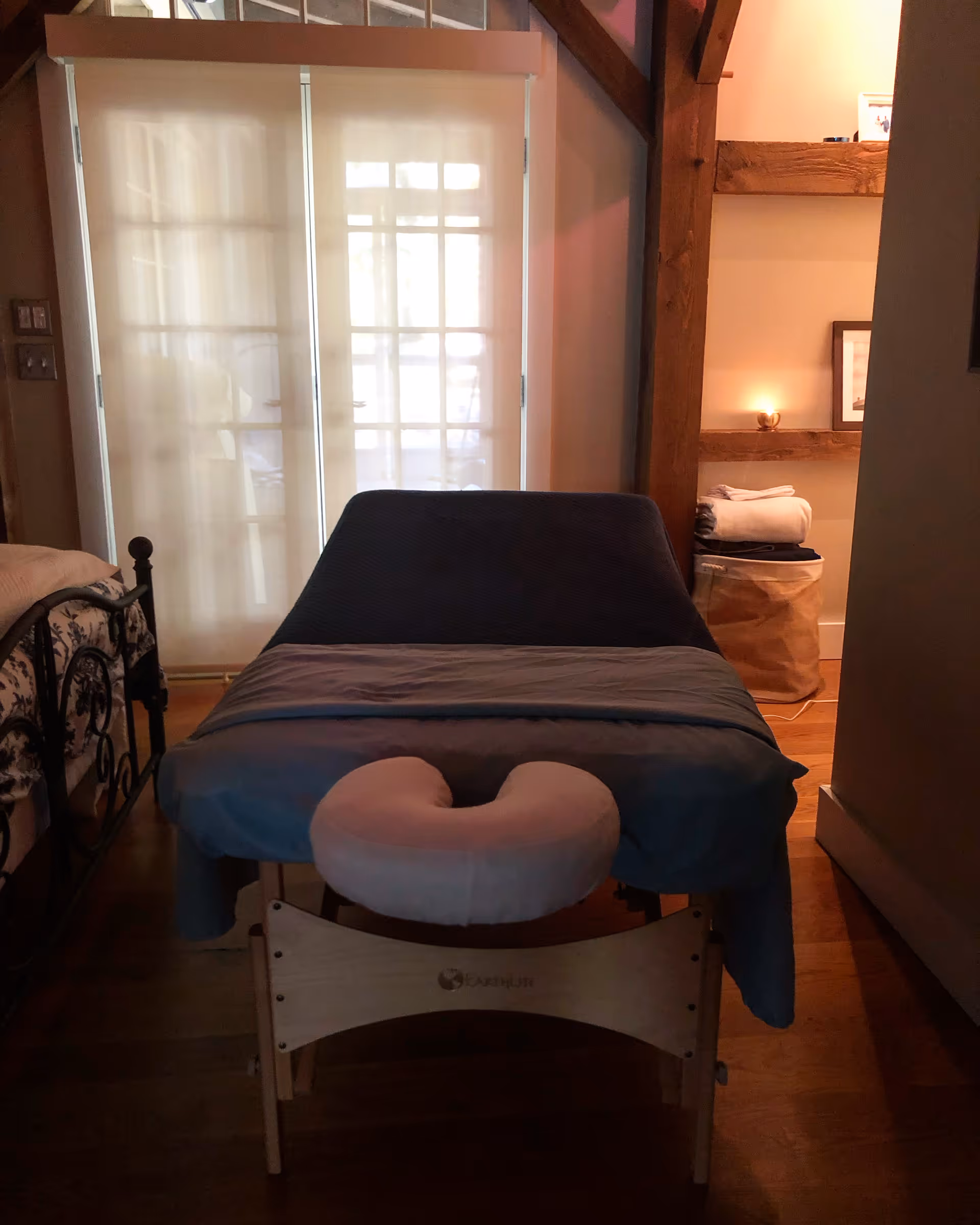 A massage therapy table in a softly lit private treatment room with wooden beams.