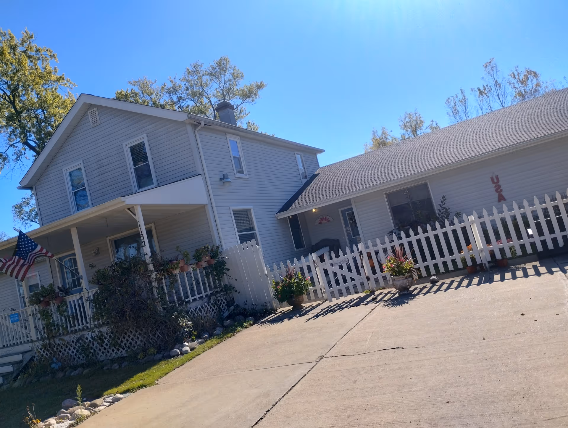 Exterior of Maple Place Assisted Living: a two-story building with a white fence and plants.