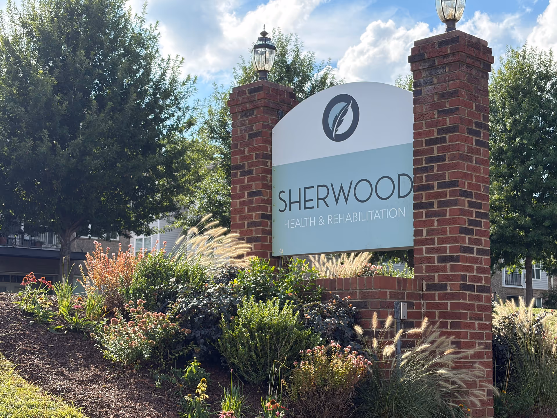 Exterior entrance sign for Sherwood Health & Rehabilitation with brick pillars and landscaping.