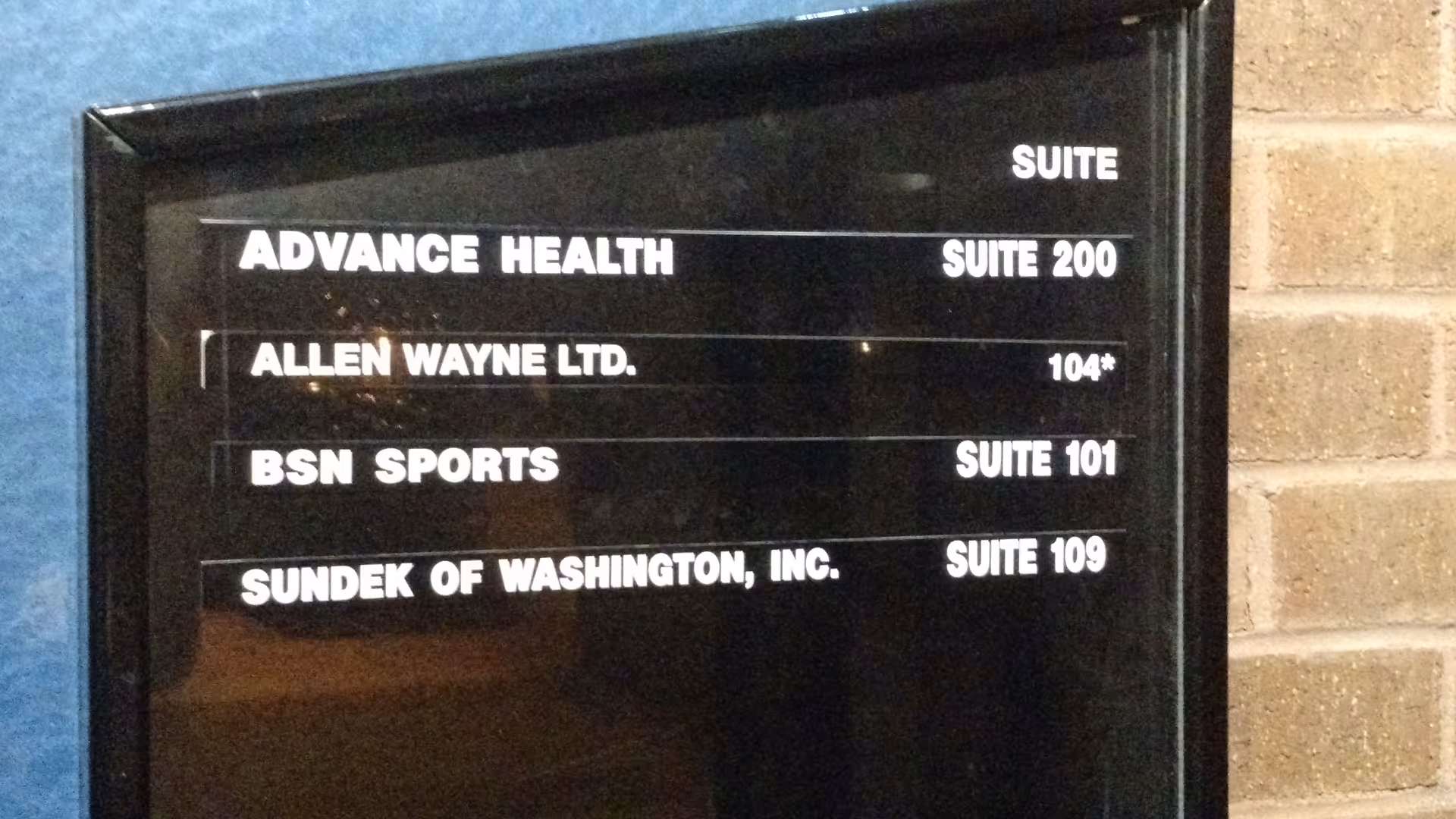 Black directory sign lists Advance Health Suite 200 and other suites on a brick interior wall.