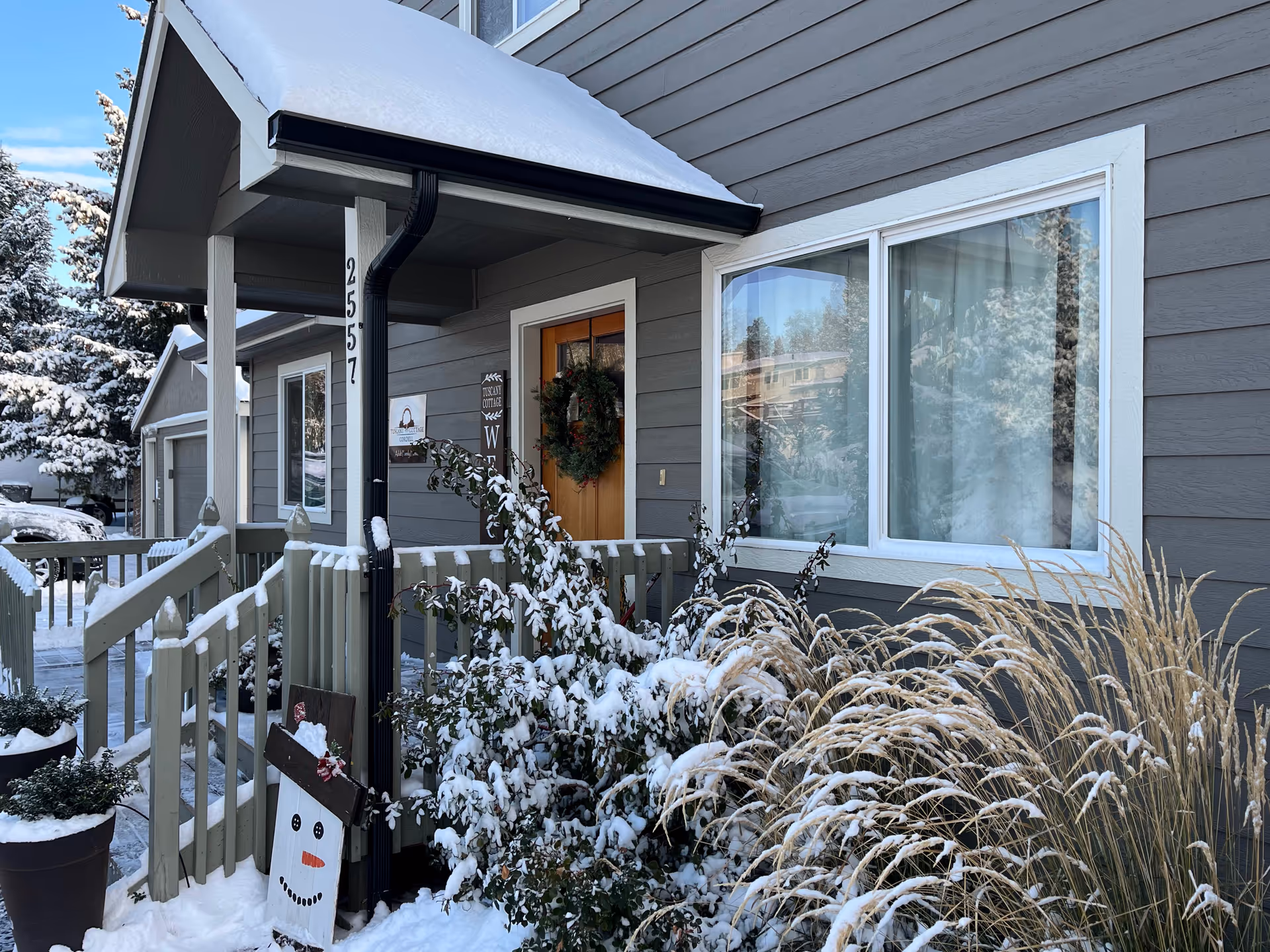Front entrance of a gray senior living home with wreath and snow.