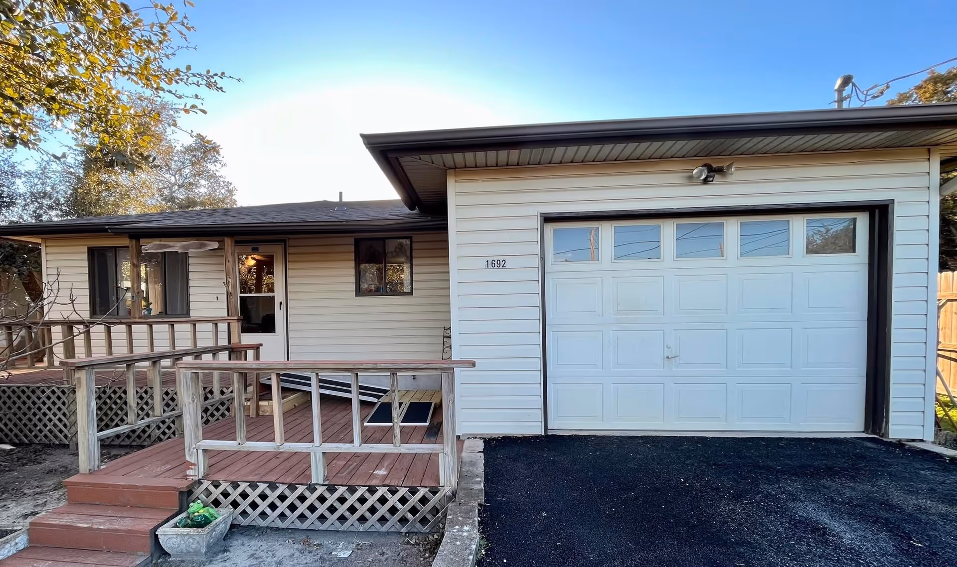 Single-story care home exterior with a wooden porch, ramp, and attached garage.