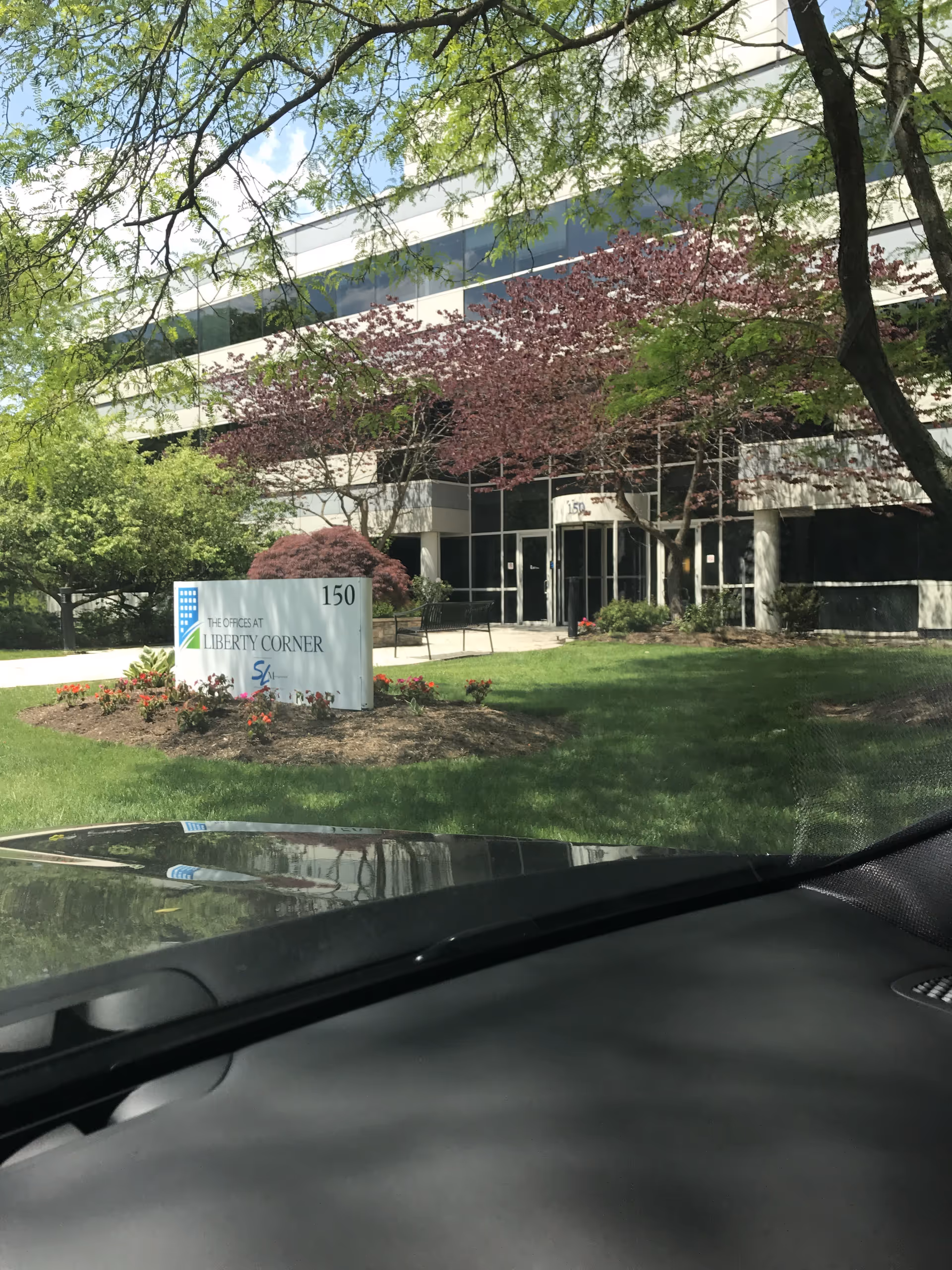 Exterior view of a modern office building with landscaped entrance and sign.