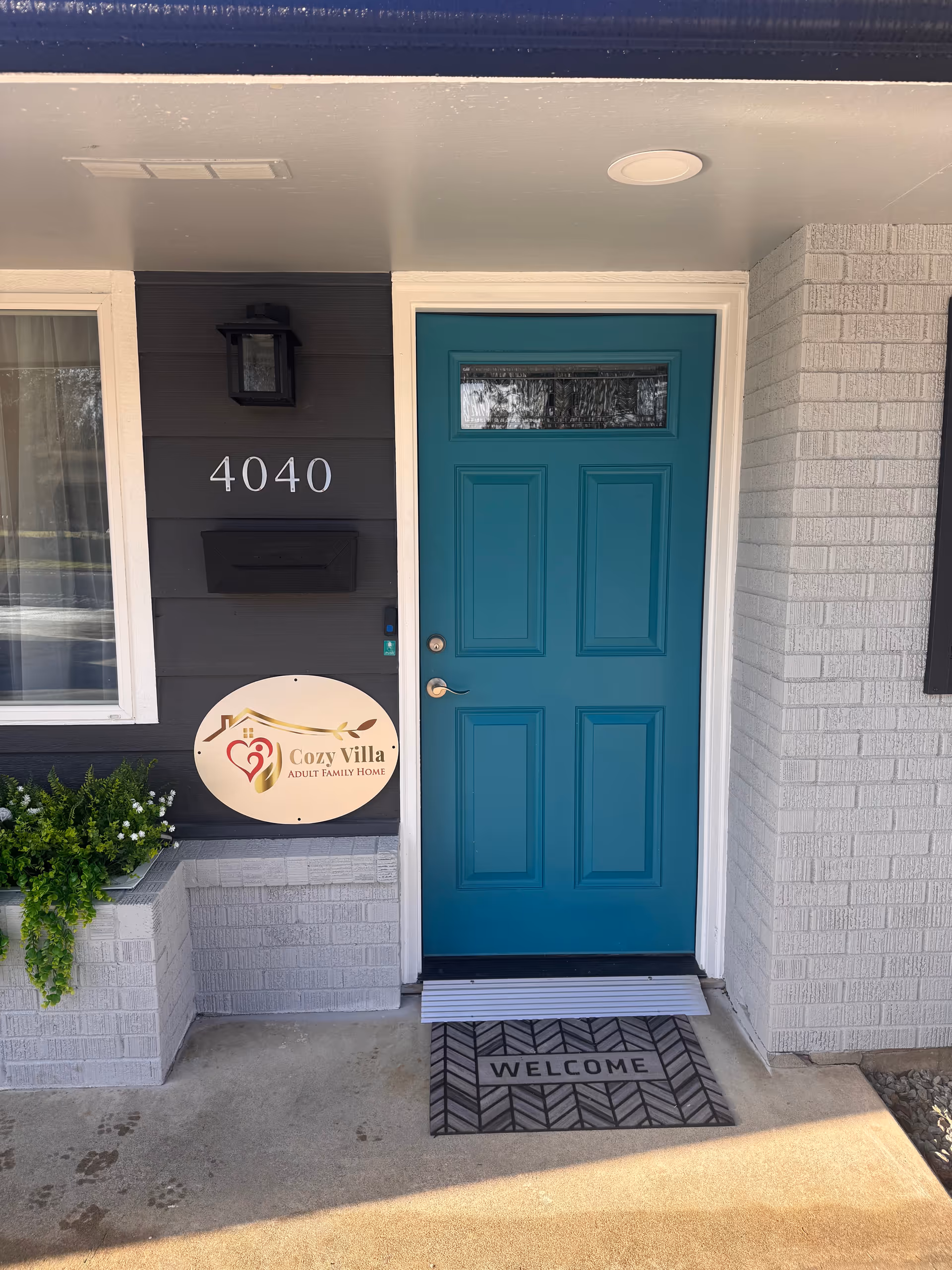 Front entrance of Cozy Villa Adult Family Home with teal door and welcome mat.