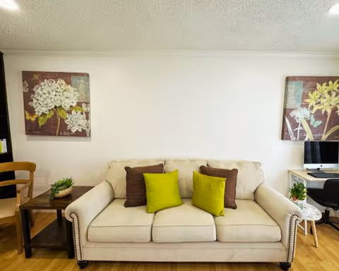 Cozy living room in Lucky Garden Care Home featuring a beige sofa and wall art.