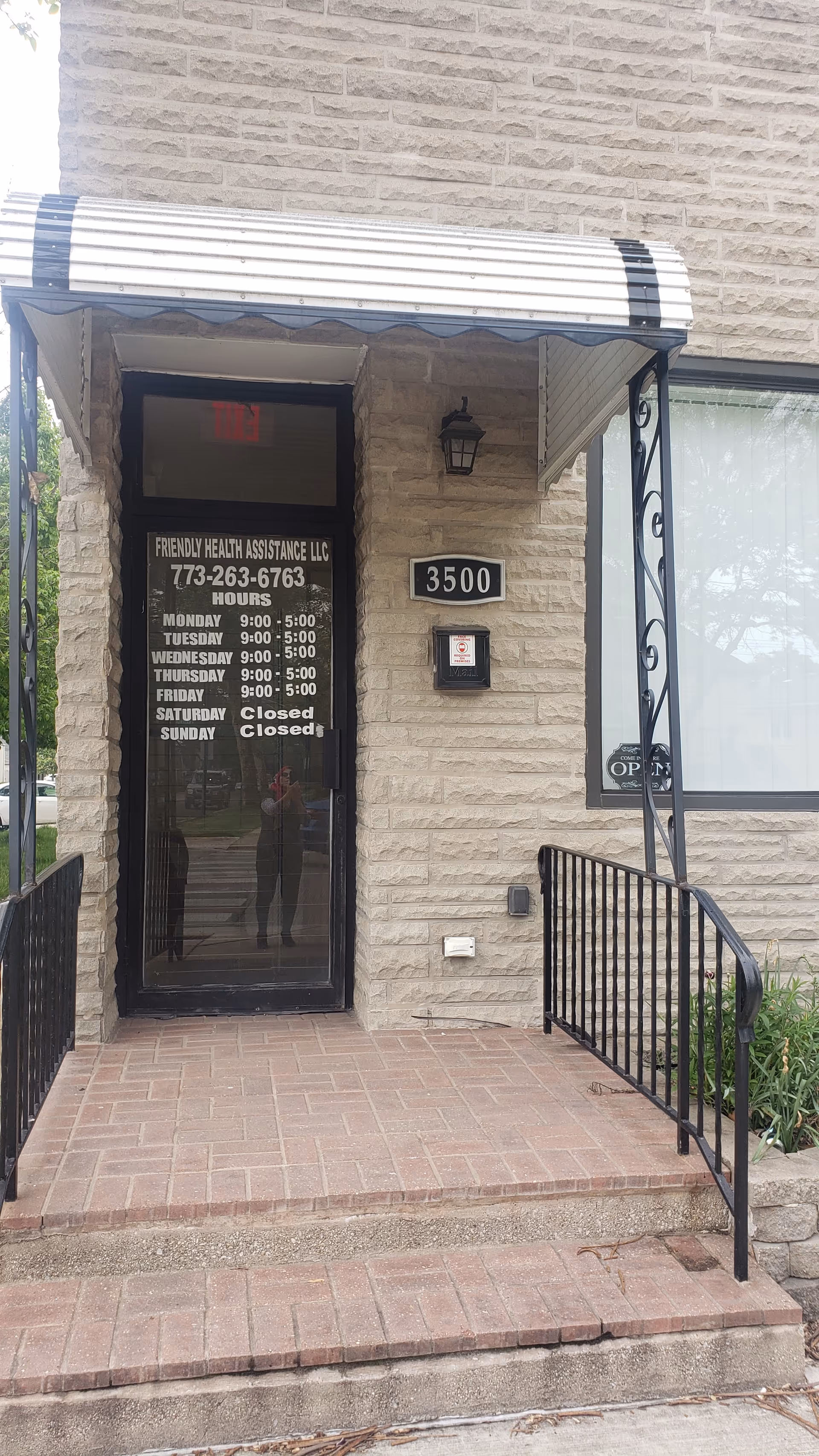 Entrance of Friendly Health Assistance LLC with hours sign and address plaque on brick facade.