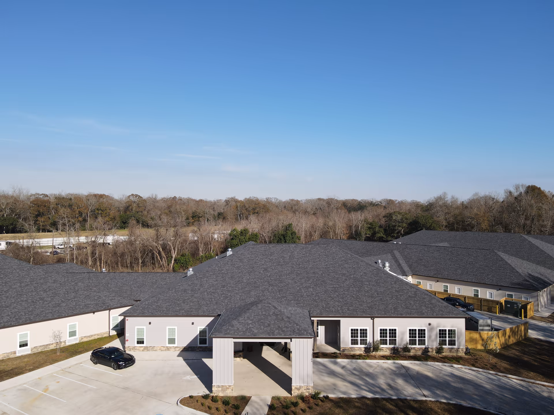A senior living community building with a covered entrance and adjacent parking lot.