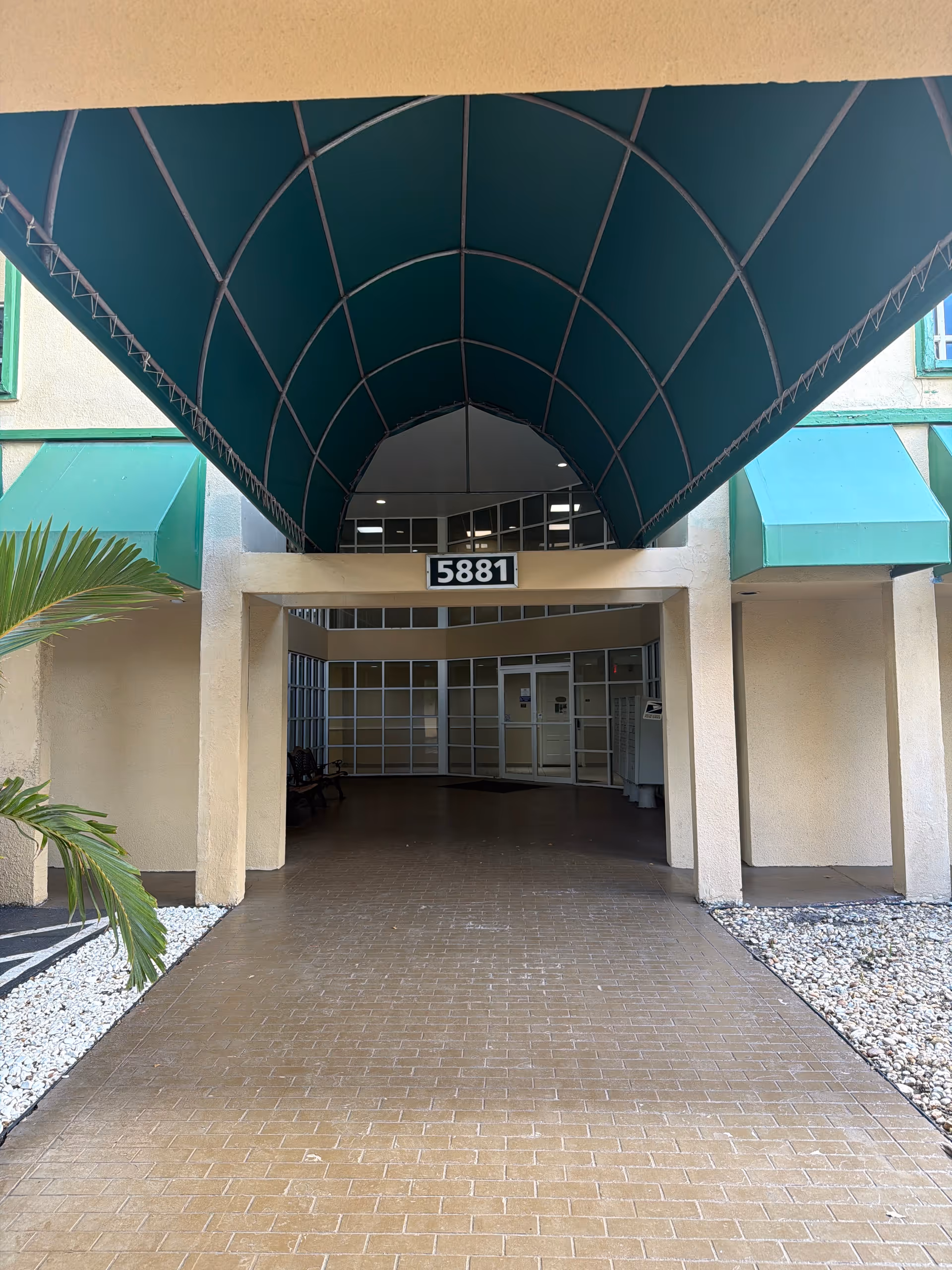 Entrance to Wellness Home Health Services building with teal curved canopy and glass doors.