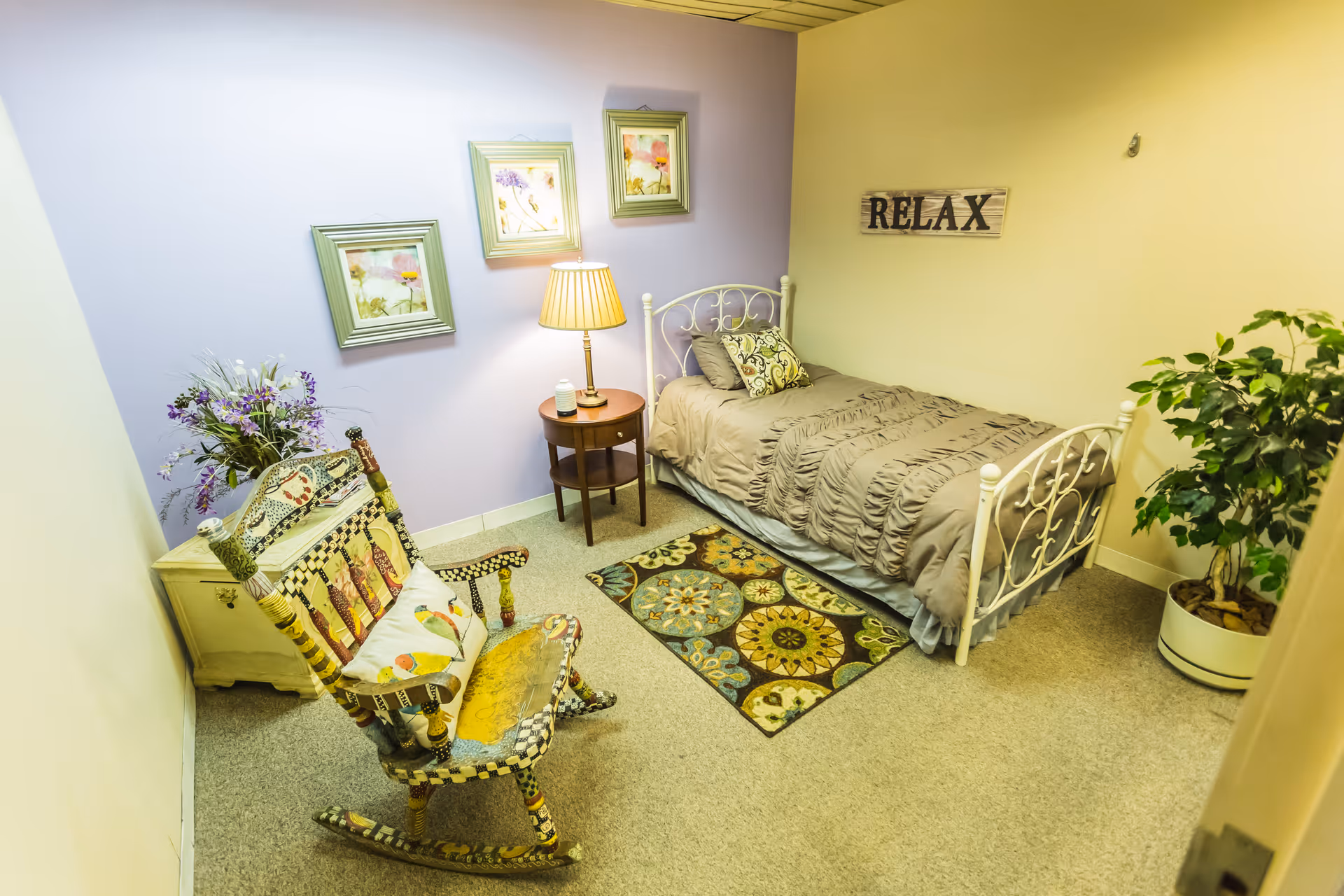 Cozy bedroom with a single bed, chair, rug, plants, and pastel walls.
