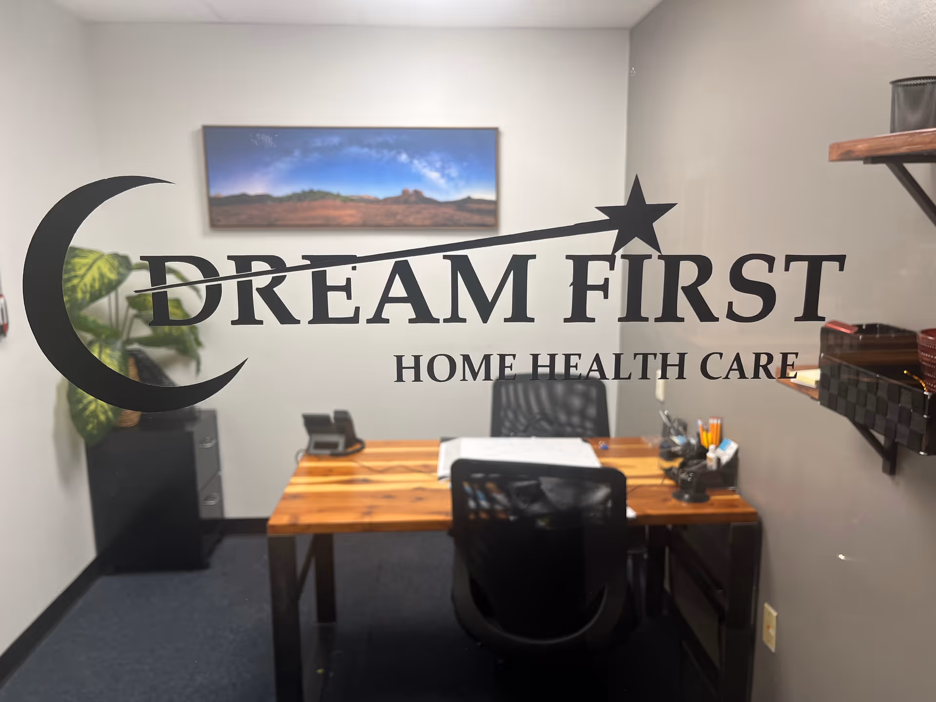 Office desk with Dream First Home Health Care logo on glass wall.