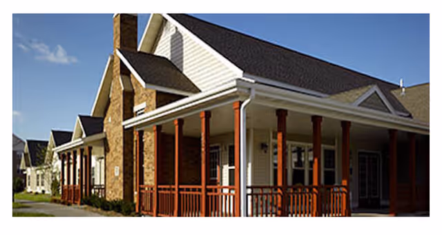 Exterior view of a senior living facility with a covered porch and red columns.