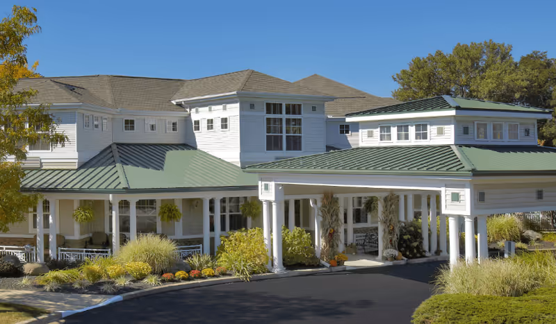 Westlake Woods Assisted Living building, white exterior, two-story, green metal roofs, with a covered entrance.