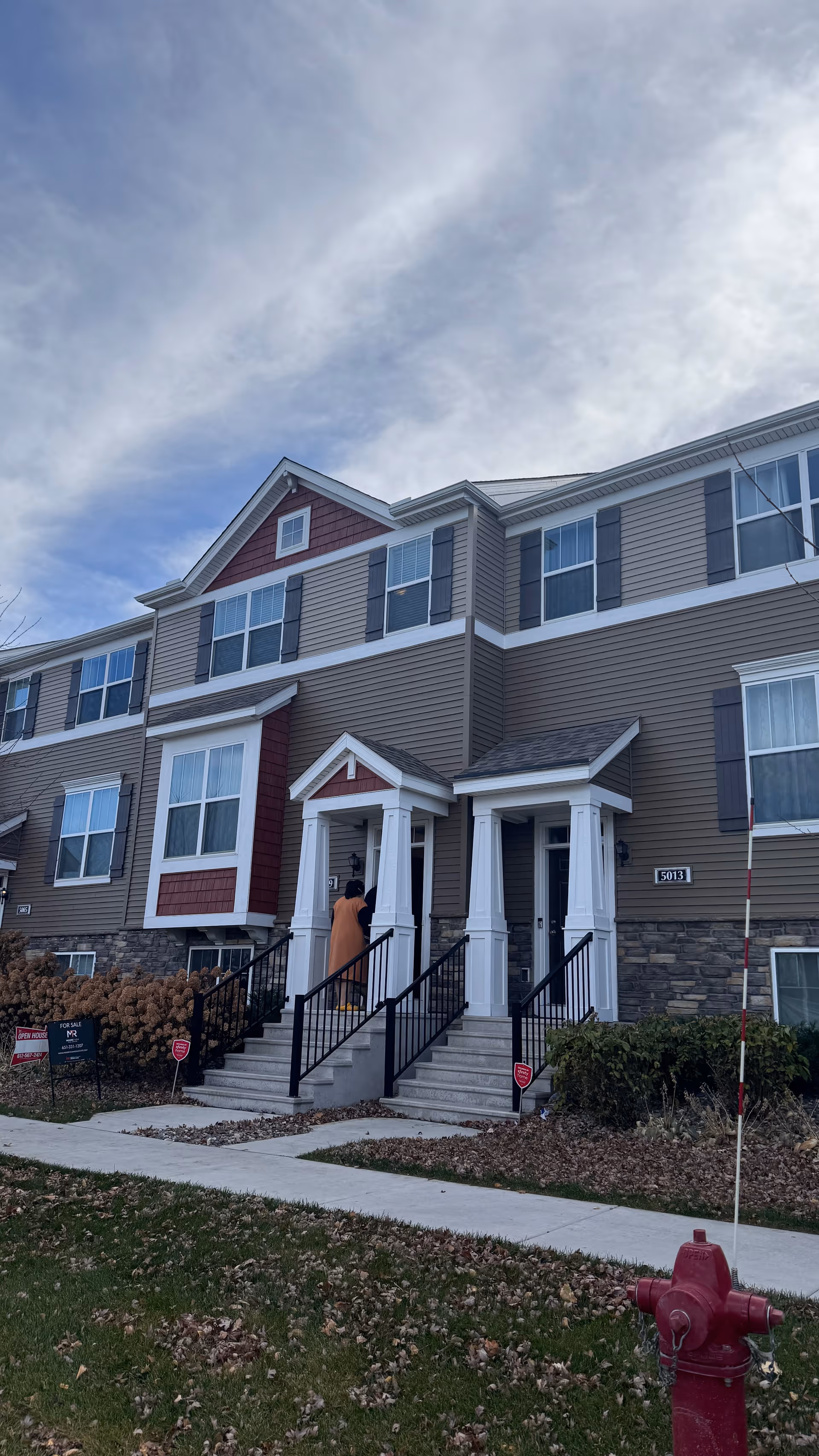 Exterior view of a multi-story senior living building with front entrances and a person on stairs.