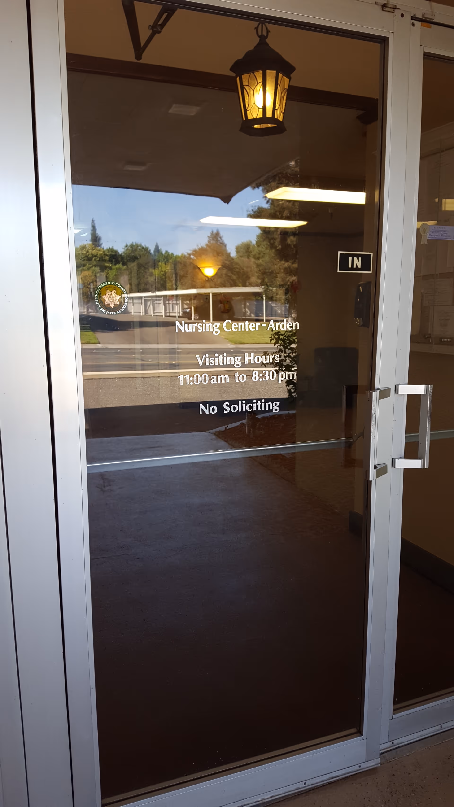 Glass entrance door with Arden Nursing Center signage and visiting hours.