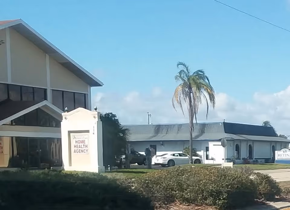 Exterior view of a care facility with sign reading Home Health Agency and palm trees