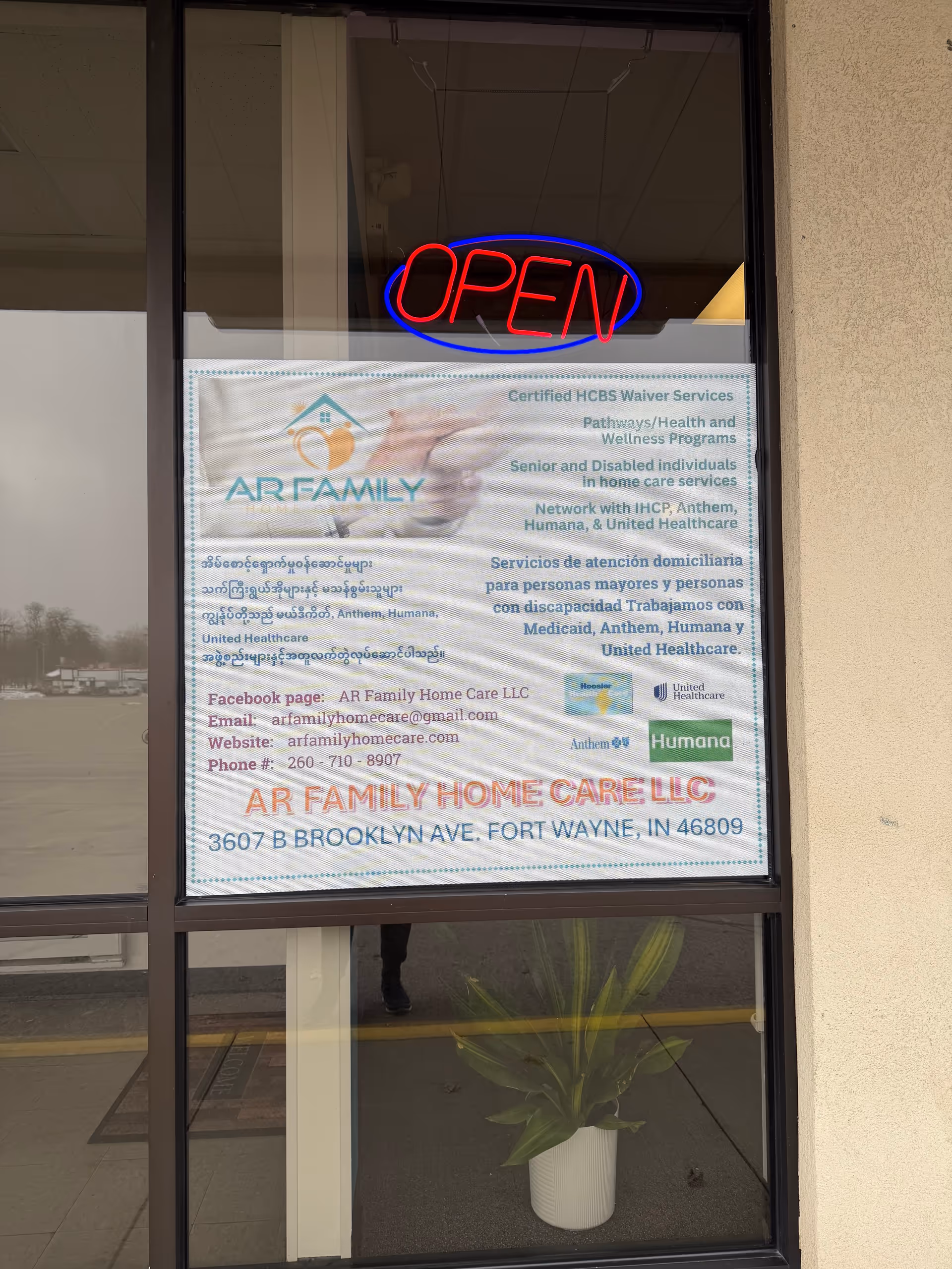 Storefront window displaying an OPEN sign and a banner for AR Family Home Care LLC.
