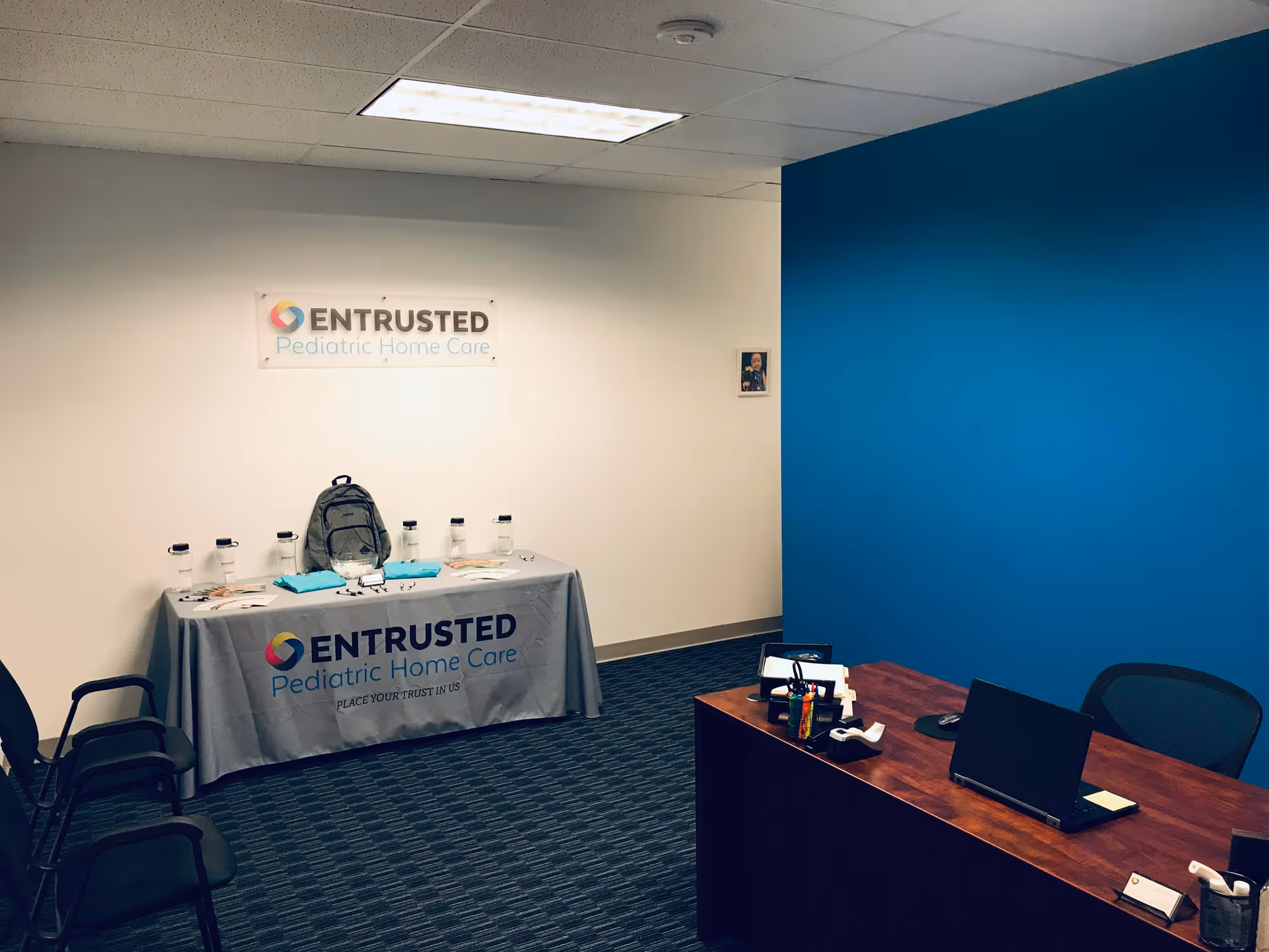 Reception area with branded table, wall sign, blue accent wall, and desk