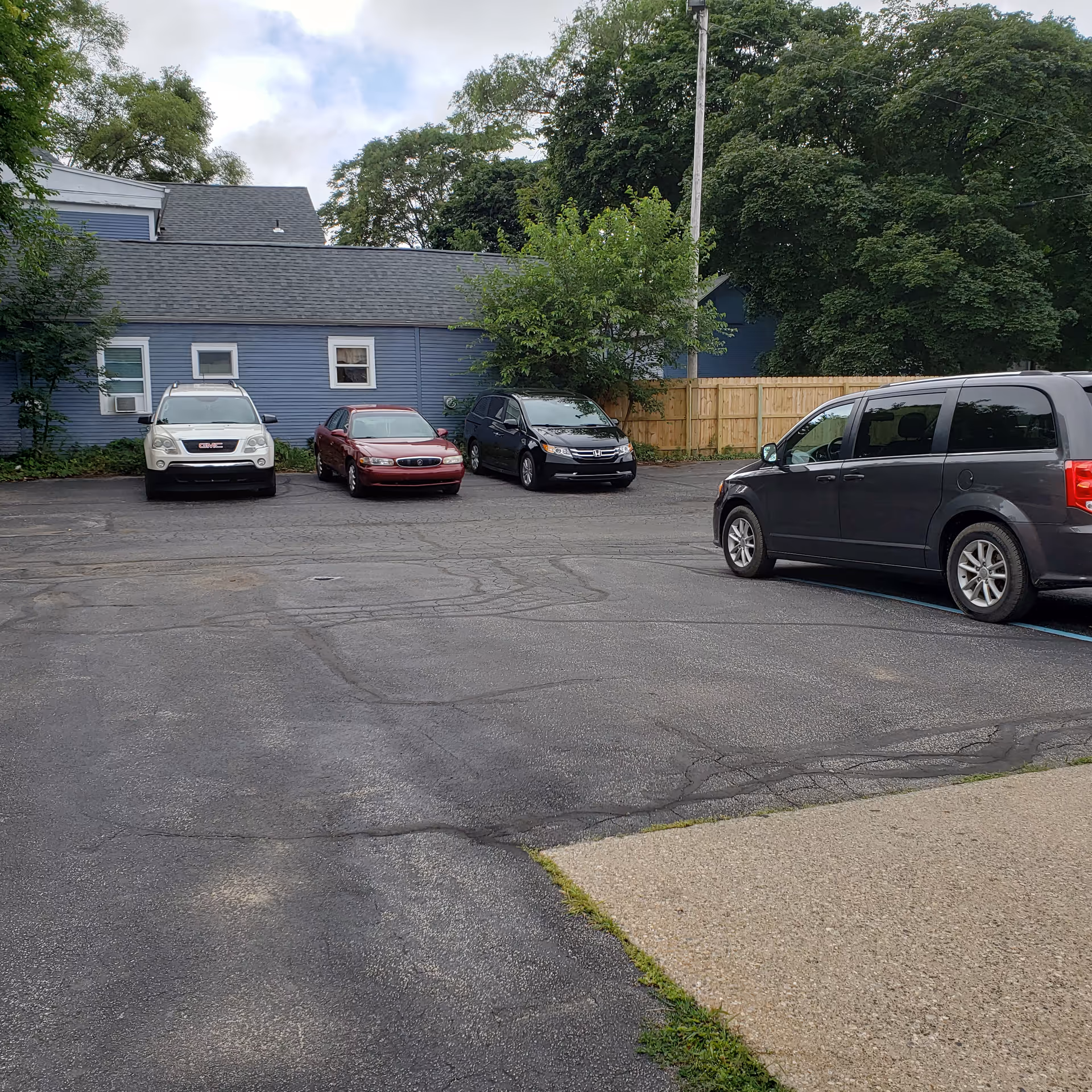 Parking lot in front of a blue building with several parked cars