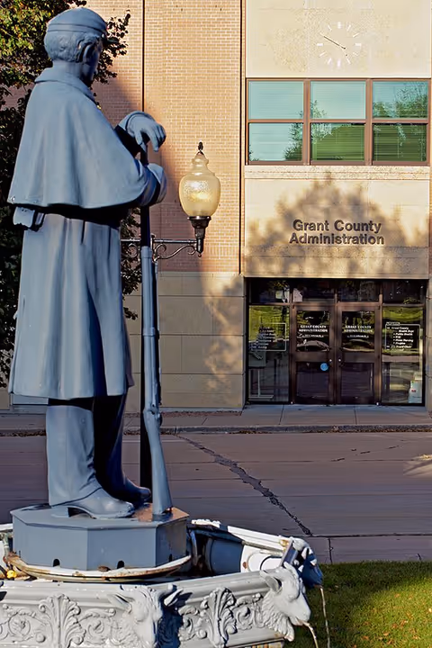 Exterior view of Grant County Administration building with statue, lamppost, and entrance.