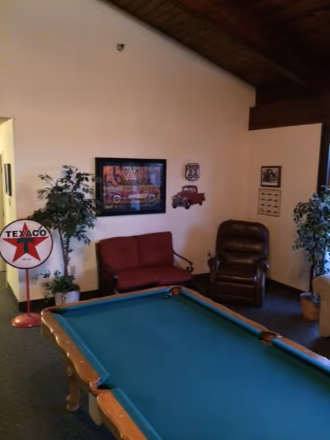 A cozy lounge area featuring a pool table, seating, and decor in a senior living facility.