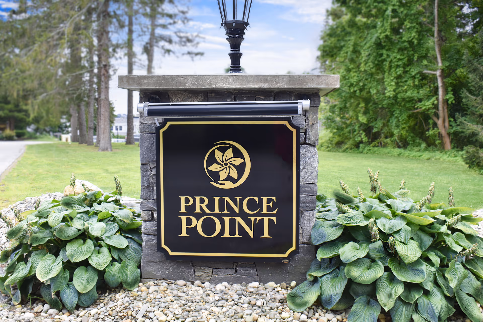 Stone entry sign reads PRINCE POINT with surrounding hosta plants and greenery.