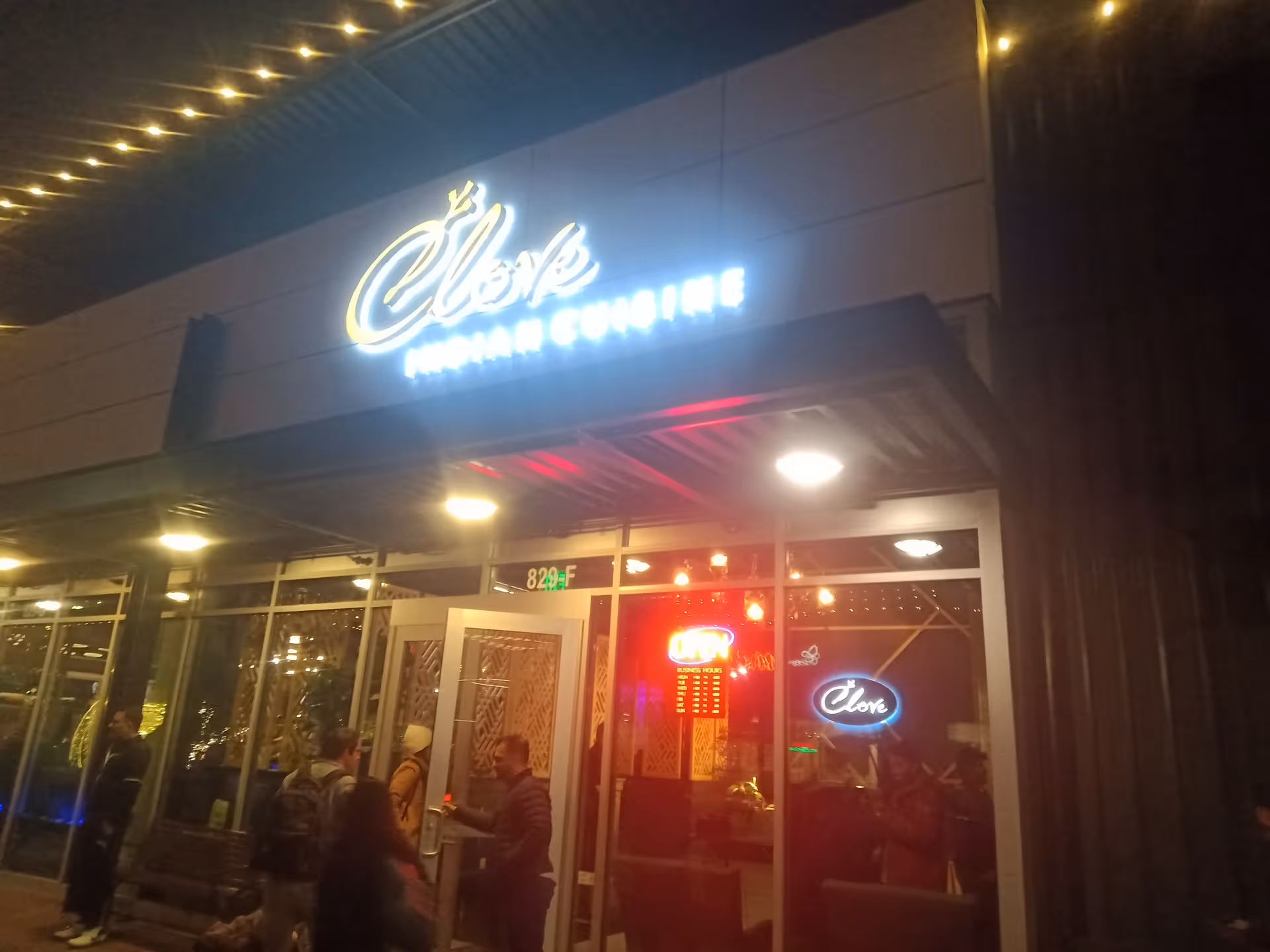 Night exterior of a facility entrance with glass doors and neon signage.