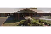 Front view of Pine View Care Center with entrance, lawn and shrubs.