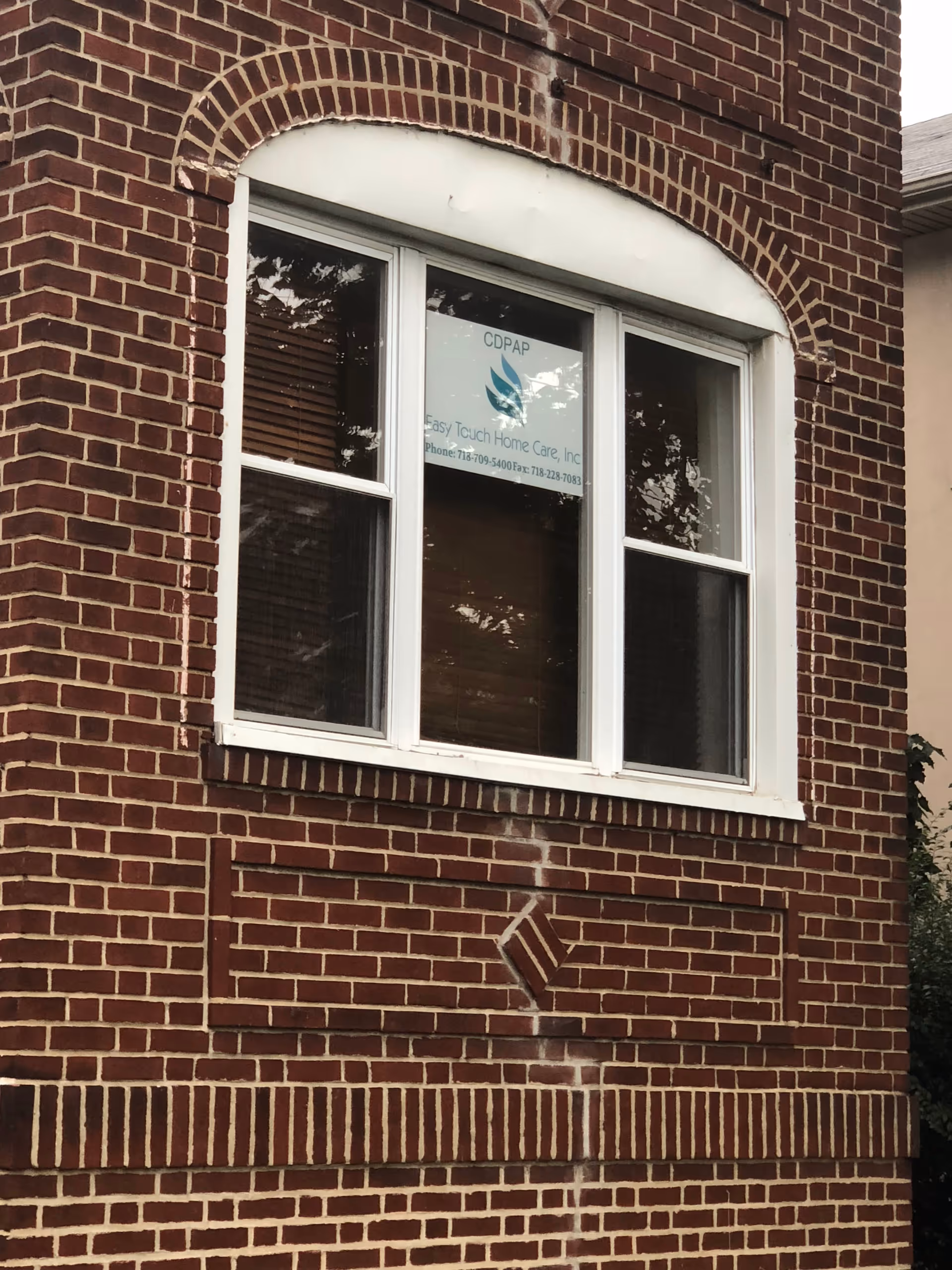 Brick building facade with a white-framed window and Easy Touch Home Care, Inc sign.