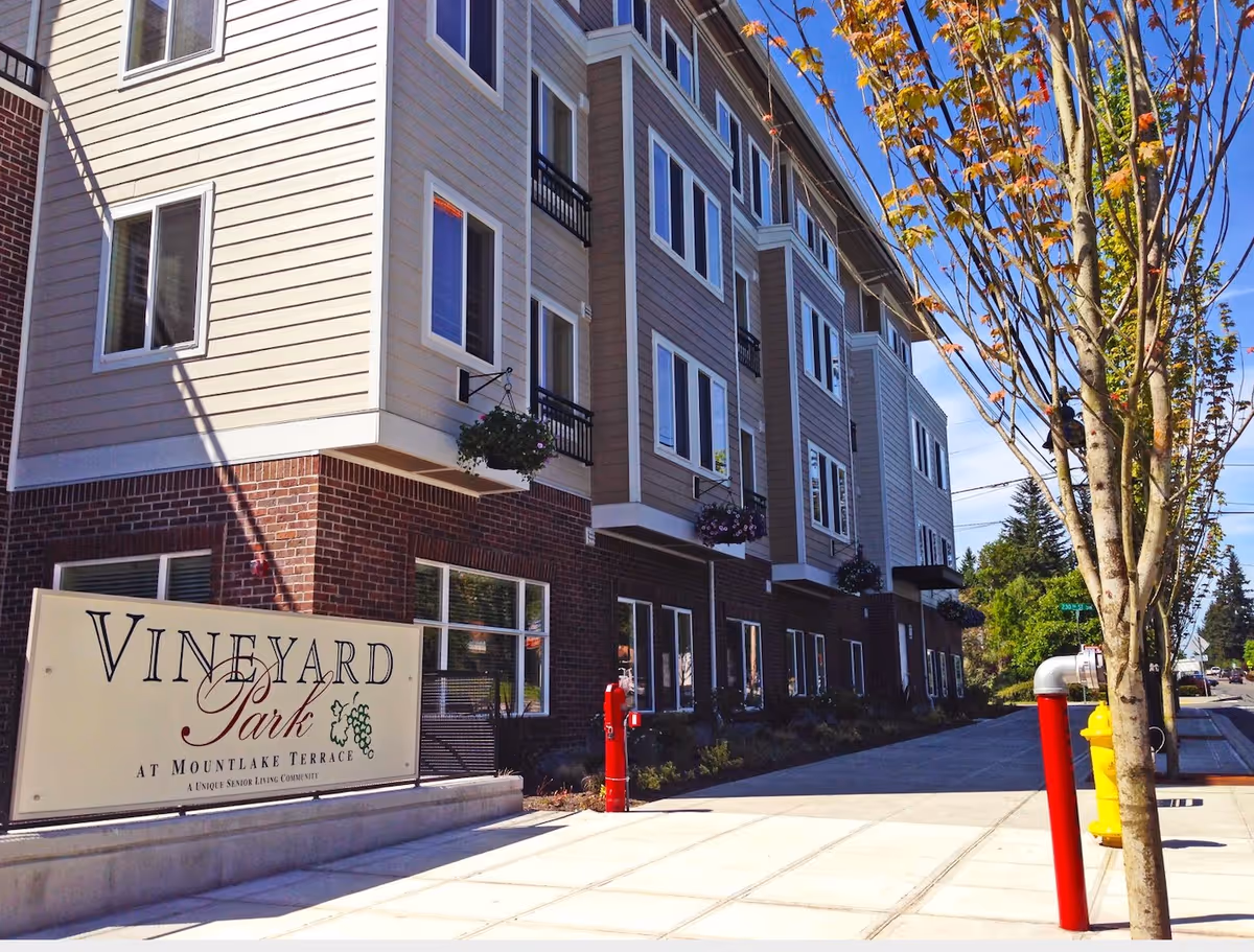 Exterior view of a multi-story senior living building with a Vineyard Park sign.