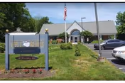 Exterior view of Apple Rehab Colchester with sign, flagpole, and parked cars.