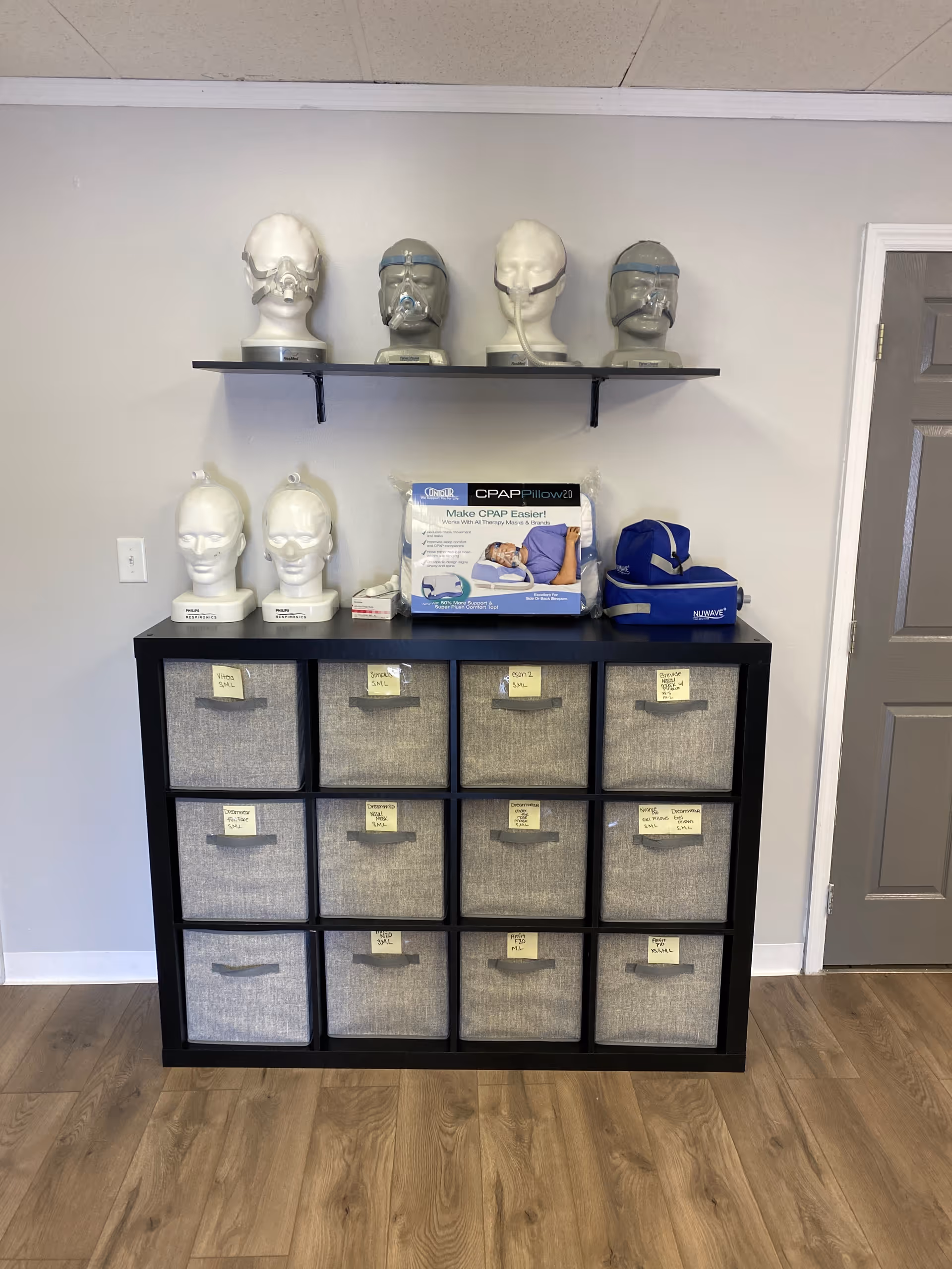 Interior storage cabinet with fabric bins, CPAP box, and medical mannequin heads on top.