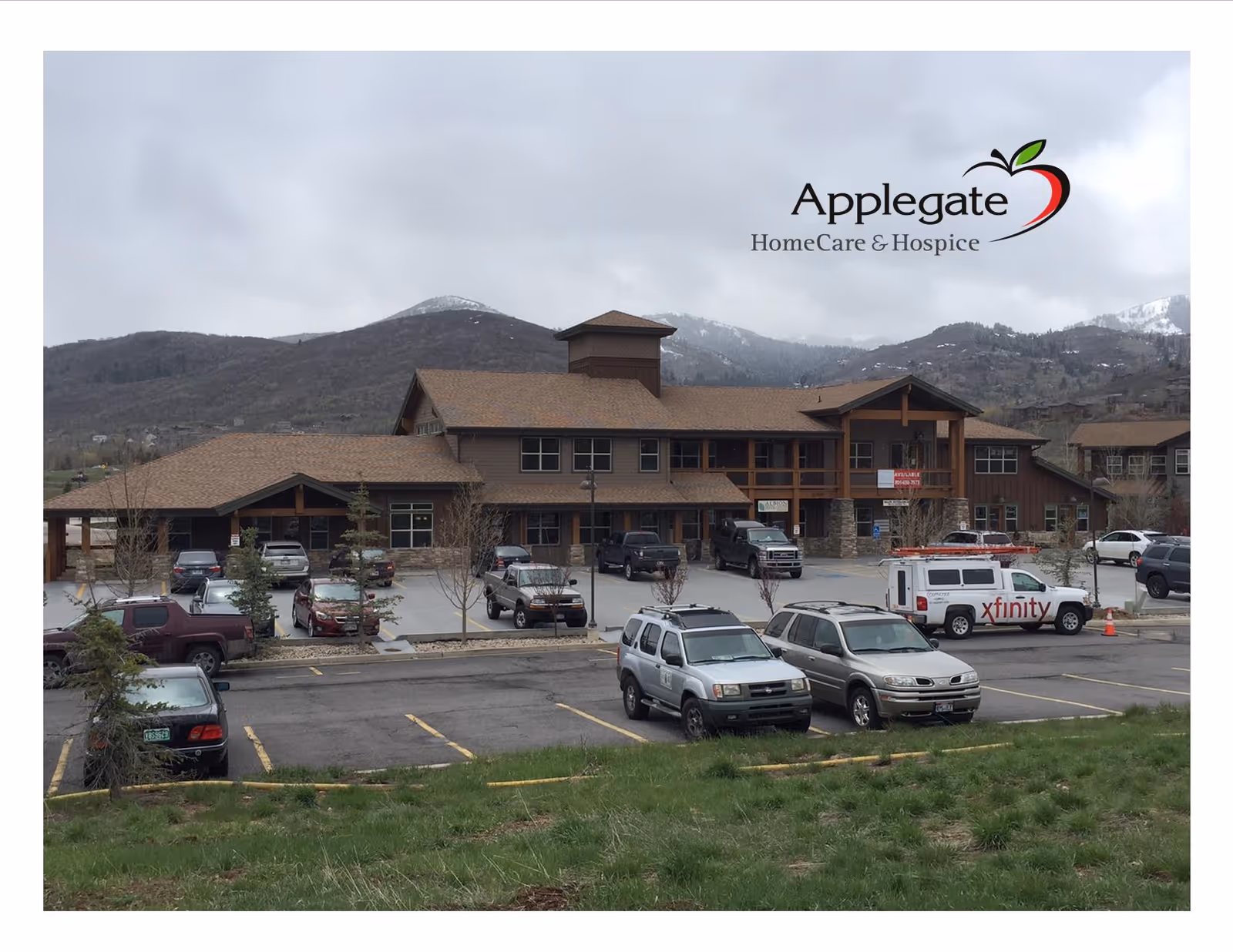 Front view of Applegate HomeCare & Hospice facility with parked cars and mountains in the background.