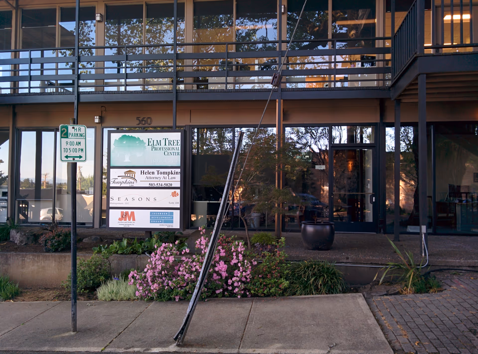Exterior view of Seasons Living building with signs, glass doors, and landscaped entrance.