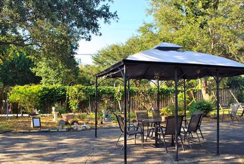 Outdoor patio with gazebo, tables, chairs, and surrounding greenery.