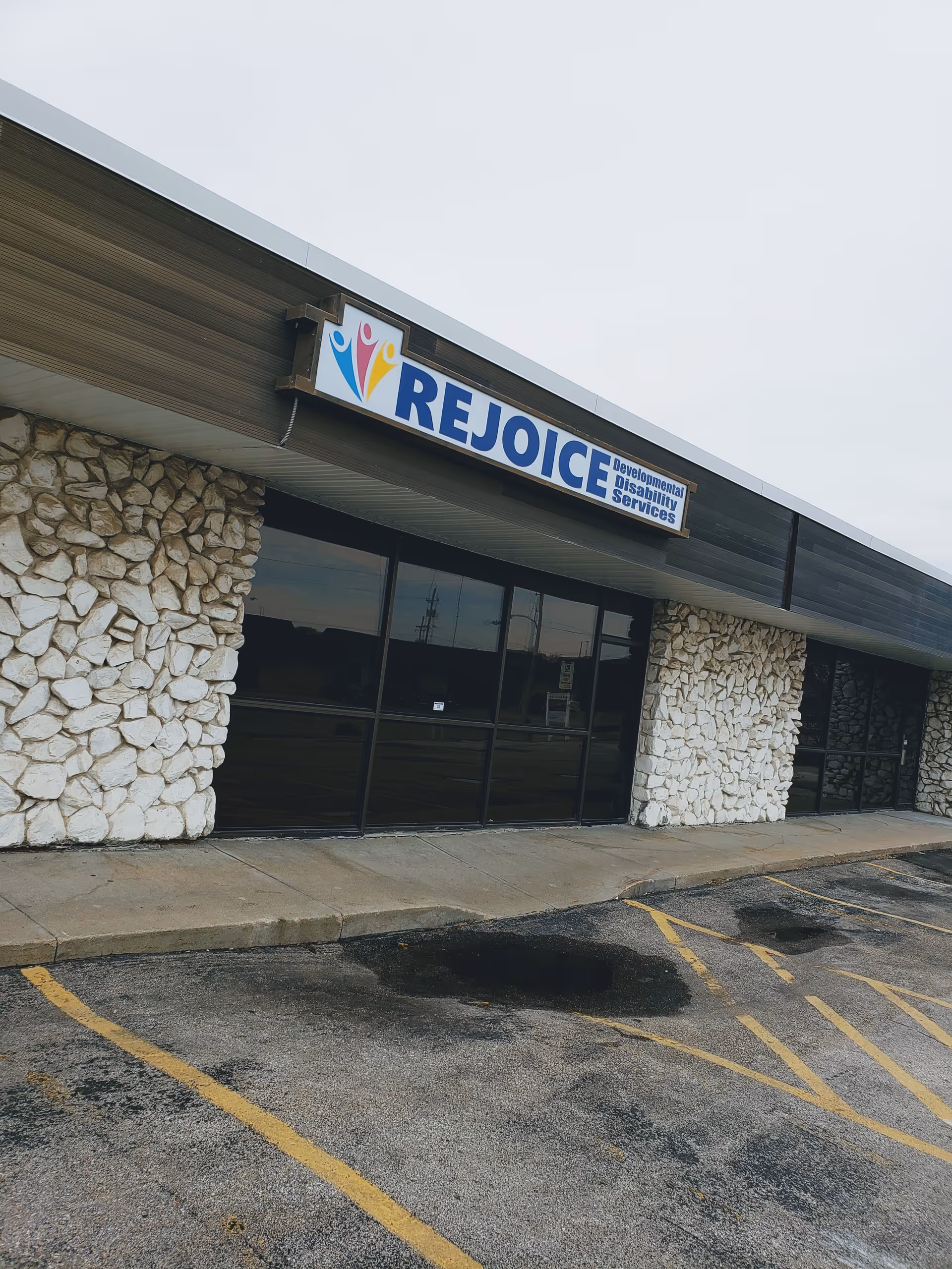 Exterior view of REJOICE facility with stone columns and large storefront windows.